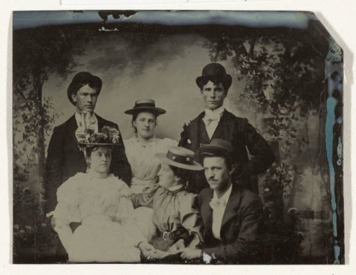 Group portrait of three men and three women, seated in an atelier with a painted backdrop (forest or park scene)