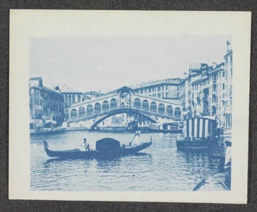 Photographic reproduction of a photograph of the Rialto Bridge over the Grand Canal in Venice, with a gondola in the foreground