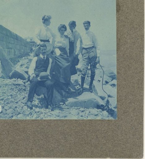 Group Portrait of Three Unknown Women and Two Men Standing and Sitting on a Rocky Beach by a Quay Wall