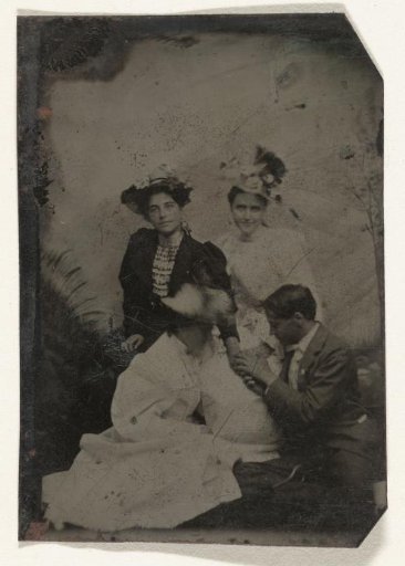 Portrait of a man kneeling before three women, holding the hand of two of them