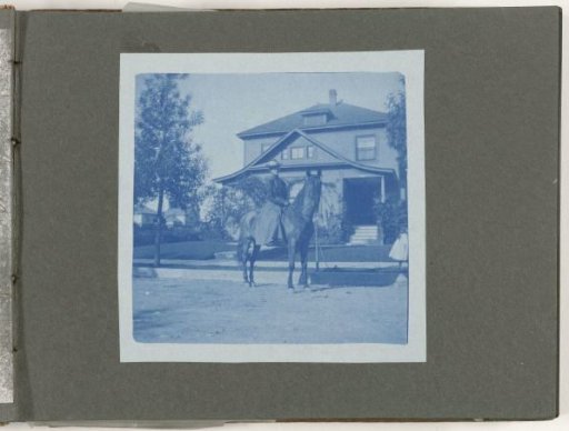 Portrait of a woman on horseback in front of a house, United States