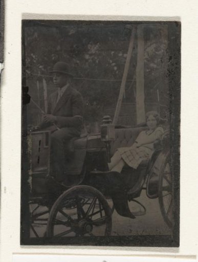 Woman seated in a carriage, with an Afro-American coachman on the box