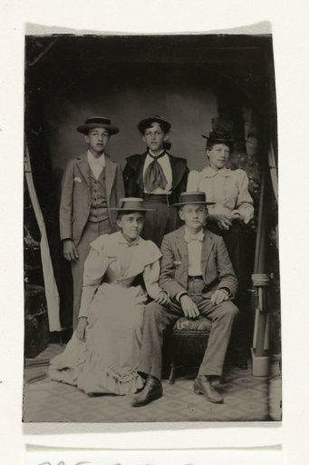 Group portrait of two men and three women, standing and seated in a cramped studio