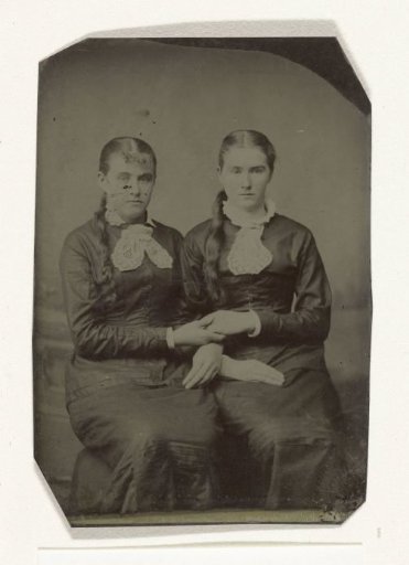 Portrait of two women sitting side by side and holding each other's hands