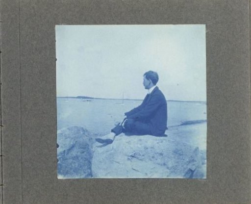 Woman in profile, sitting on a rock by the sea, United States