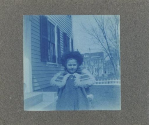 Child standing beside a wooden house, United States