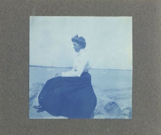 Woman in profile, sitting on a rock by the sea, United States