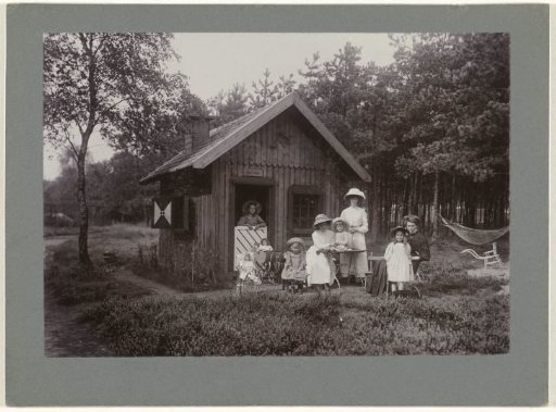 The photographer's children (Renée, Thelma, Irène and Sacha) with their mother, two nannies and mother at a playhouse (?), 'Sand cottage'