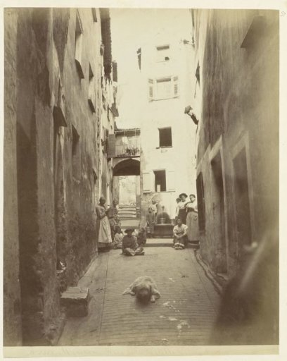 A narrow street in Menton with women and children in the streetscape