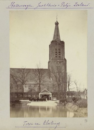 People in traditional dress posing in front of the church tower of Kloetinge