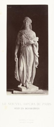 Marble statue of a woman in a robe and veil over her head, holding a bouquet of flowers in her left hand.