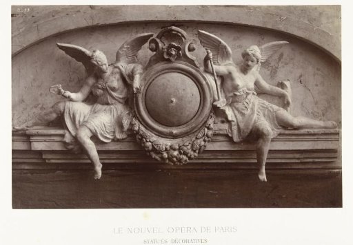 Two statues of female angels holding mallets, seated on either side of a medallion, situated above a doorway