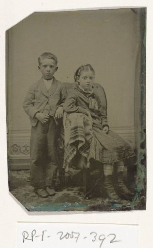 Portrait of a girl and boy (brother and sister?), seated and standing in a studio setting