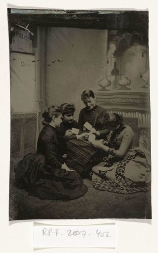 Portrait of four young women, seated in front of a painted backdrop (salon-like interior), playing cards
