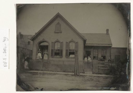 View of a wooden house with approximately nine people standing in front of it or in the doorways, USA