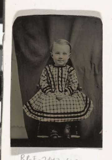Portrait of a child, seated on a chair in a studio setting (with the mother undoubtedly holding the child (quasi-)invisible behind the backdrop ('hidden mother')