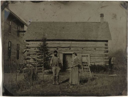 View of a wooden house or barn with a man and woman in front