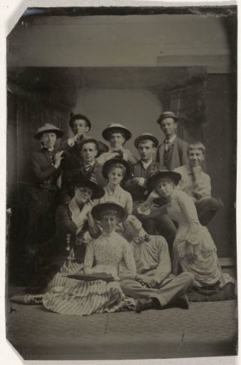 Group portrait of six men and six women, standing and seated before a painted backdrop (architecture)