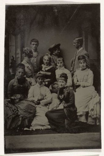 Group portrait of two men and eight women, standing and seated before a painted backdrop (salon-like interior)