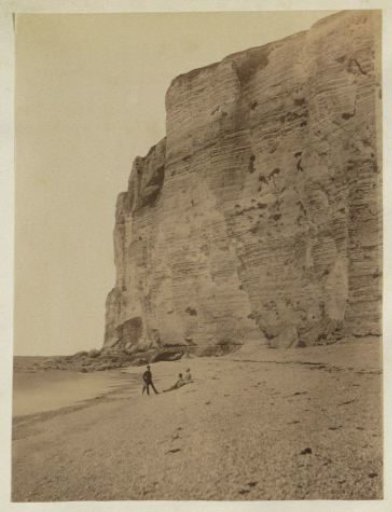 Group on a beach before a rock wall, probably at Étretat