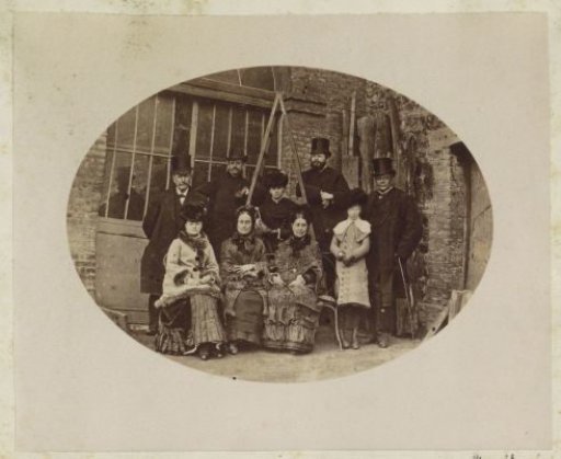 Group portrait of four men, four women and a girl standing by a barn in France