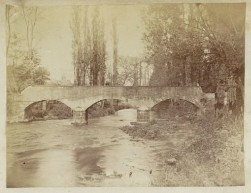 Two persons on a stone bridge over a stream in France