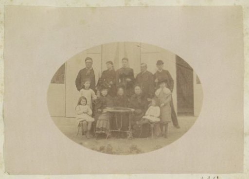 Group portrait of three men, five women and four children standing at a table in France