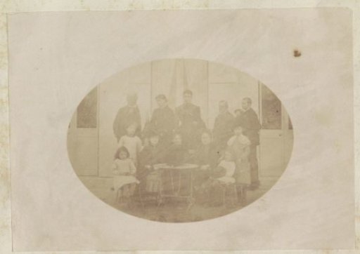 Group portrait of three men, five women and four children standing at a table in France