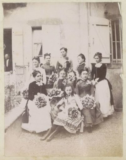 Group portrait of nine women holding bouquets during a wedding in France