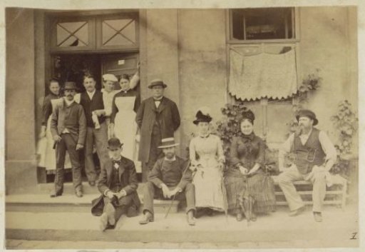 Group portrait of a company including 'Henri' in front of an establishment in France