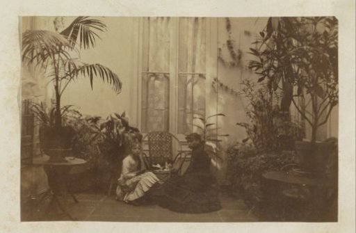 Two girls sitting with a cat in a courtyard in France