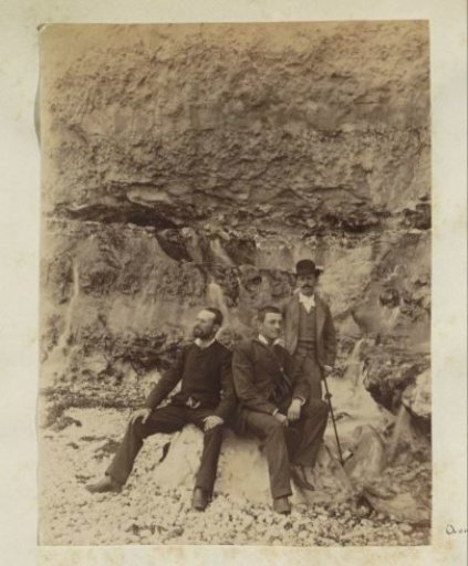 Three men standing before a rock wall in France