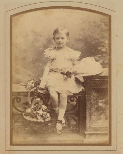 Studio Portrait of a Girl Sitting on a Balustrade with a Flower Basket in Her Hand