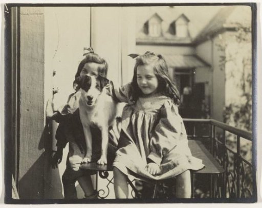 Two girls and a dog on a balcony at the rear of a house
