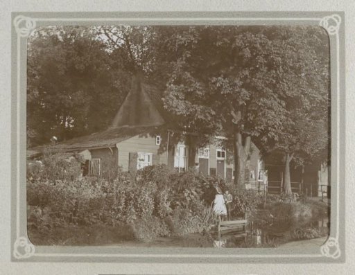 House with a barn among the trees, two children by a ditch in the foreground