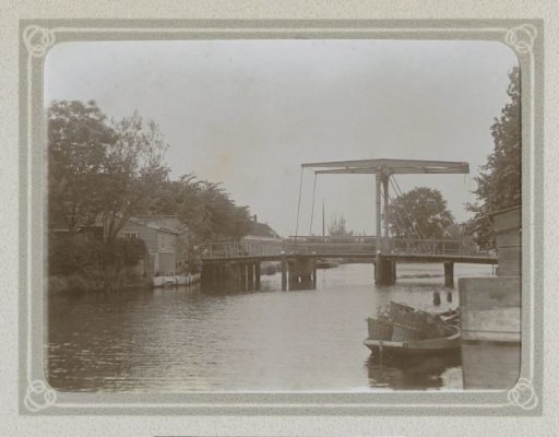 Drawbridge over a body of water near houses, with a boat loaded with wicker baskets in the foreground