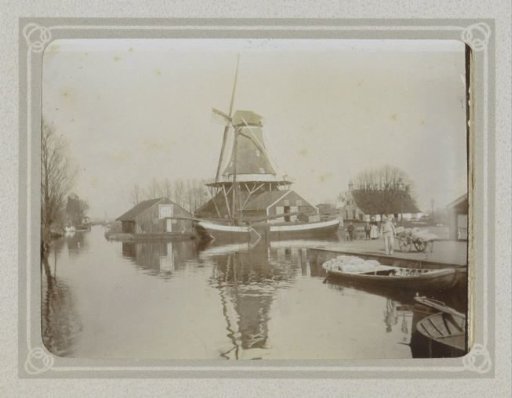Windmill by a body of water with boats
