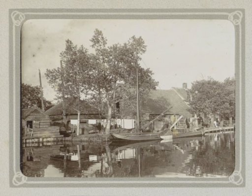 Farmhouse with a barn and a haystack on a waterway, with a flat-bottomed boat in the foreground