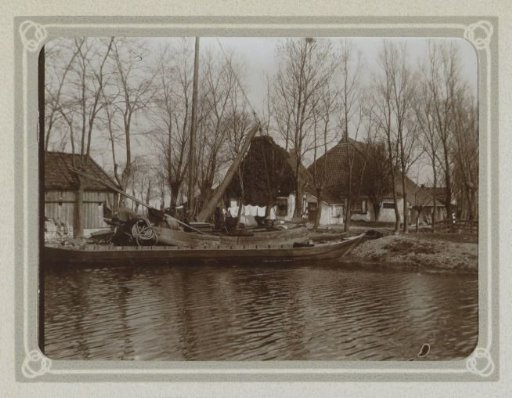 Farmhouse with a barn along a waterway, with boats in the foreground