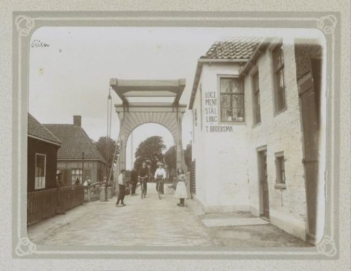 Street in Rien with a drawbridge, lodging and stable T. Broersma, cyclists, and children