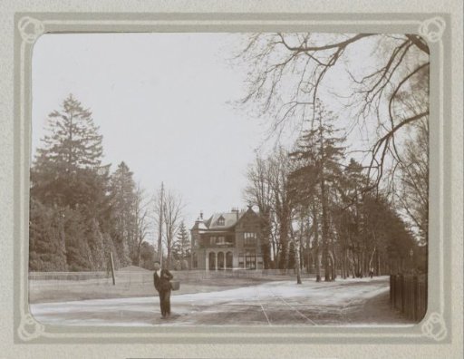 Country house on an avenue, in the foreground a man with a bucket