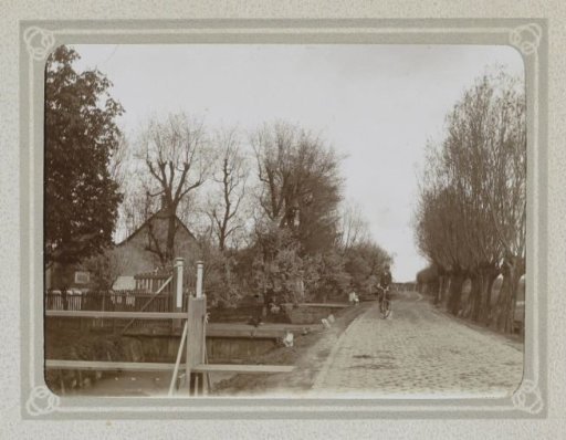 Man cycling next to a ditch in a village
