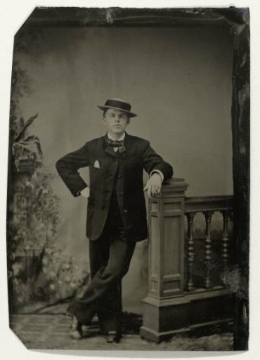 Portrait of a young man, standing by a balustrade before a painted backdrop