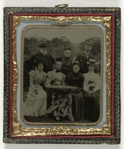 Group portrait of five women and two men around a table in the open air
