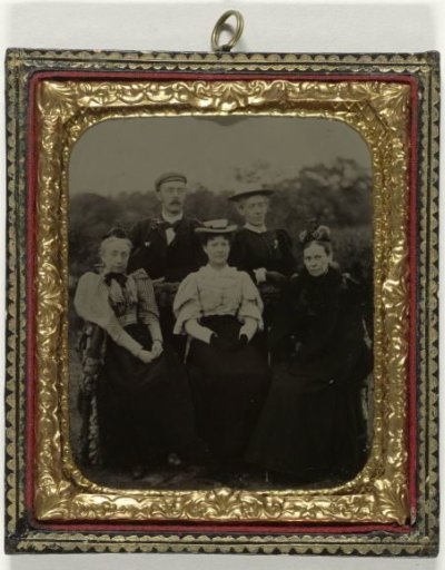 Group portrait of four women and a man around a table in the open air