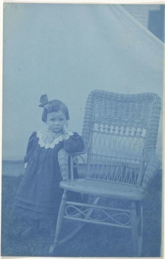 Portrait of an unknown young girl, standing next to a chair