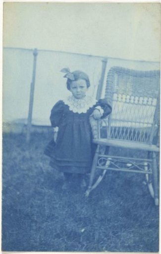 Portrait of an unknown young girl, standing next to a chair
