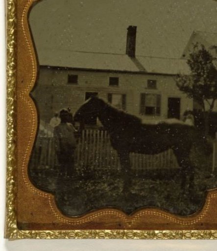 Man and horse in front of a house, backlit