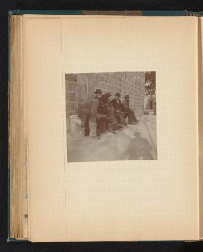 Group of Older Men with Hats Sitting on a Bench in front of a Stone Wall in Ajaccio, Corsica