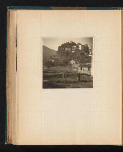 Hill with houses and women working on the fields in front of them in Corté, Corsica